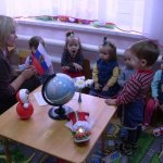 Педагог показывает детям флаг России