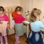 Three girls wash and dry their hands